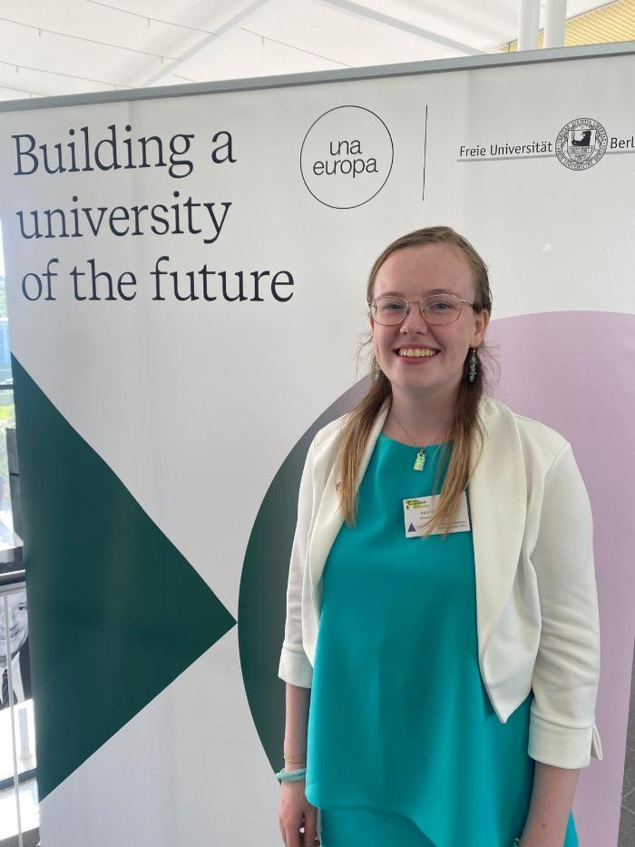 A student in front of a banner.